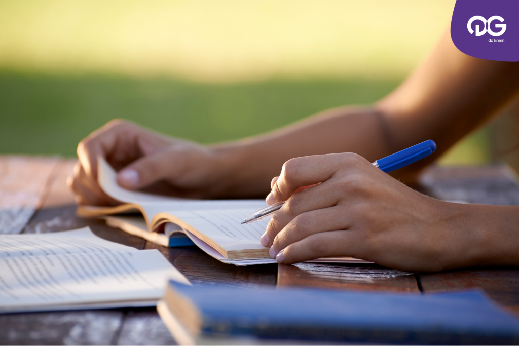como estudar redação - um aluno segurando uma caneta nas mãos enquanto escreve em um caderno.